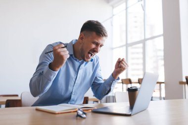 Uzakta web tasarımı okuyan neşeli bir erkek öğrenci. İnternette araştırma yapmak için dizüstü bilgisayarda öğrenim görüyor. Netbook teknolojisinde wifi 'ye bağlanan mutlu beyaz adam serbest çalışmaktan çok memnun.
