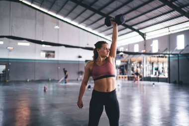 Spor salonunda egzersiz yaparken ağırlık kaldırmak ve antrenman yapmak için dambıl kullanan beyaz kadın. Kas şeklindeki güçlü kadın spor ekipmanlarıyla egzersiz yapıyor.