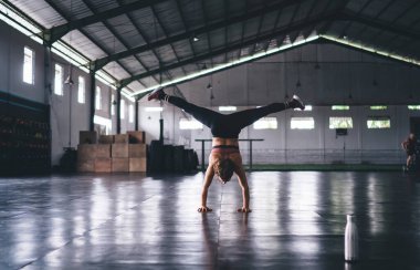 Spor salonundaki antrenman sırasında denge kuran kadın sporcuların arka planda duruşları, eşofmanlı zayıf bir kadın enerji egzersizleri sırasında amuda kalkarak sağlıklı yaşam tarzını koruyor.