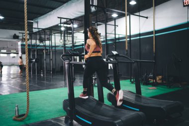 Aktif kıyafetlerle koşmaya kararlı kadın koşucu antrenman sırasında koşu hedeflerine ulaşır, spor salonundaki koşu bandı simülatöründe atletik gücü eğiten zayıf beyaz kadın.