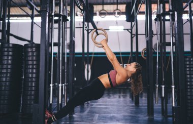 Formda genç bir kadın spor salonundaki spor salonundaki antrenmanlara katılıyor, beyaz vücutçular egzersiz yapmak ve zindelik duygusunu sağlıklı bir yaşam tarzında tutmak için sıkı çalışıyor.