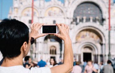 Kırpılmış kadın turist, Venedik 'te yaz tatillerinde antik mimari binaları fotoğraflamak için cep telefonu kamerası kullanıyor, kadın akıllı telefon teknolojisiyle seyahat videosu çekiyor.
