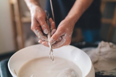 Çamur çömlek yaptıktan sonra kadın heykeltraşın suda ahşap aletleri yıkadığı görüntüler. Küçük işletme ve girişimcilik kavramı. Ev hobisi, eğlence ve boş zaman fikri. Sanat stüdyosu