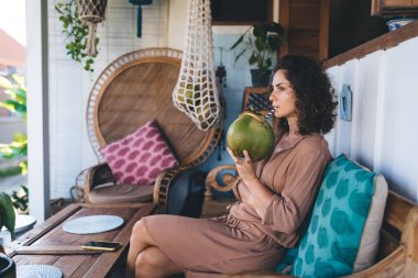 Kafe terasındaki tefekkür eden Kafkasyalı müşteri hafta sonu eğlencesinde lezzetli hindistan cevizi içecekleriyle ferahlatıcı, gündelik giysiler içindeki kadın meyve suyu ya da kokteyl içerken kafa yoruyor.