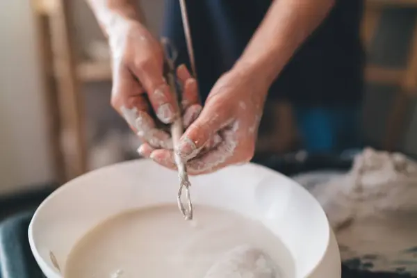 stock image Cropped image of female sculptor washing wooden tool in water after making clay pottery. Concept of small business and entrepreneurship. Idea of home hobby, entertainment and leisure. Art studio