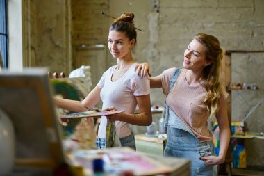 Resim atölyesi sırasında resim yapan kadın profesyoneller beraberlik sırasında ustalık tekniklerini tartışıyorlar. Stüdyodaki eğitim derslerinde bilgi veren yetenekli öğretmen.