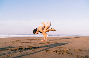 Eşofmanlı çıplak ayaklı kadın yogi ABD 'de okyanus kenarında hatha sporu yapıyor. Sağlıklı yaşam tarzını koruyor. Beyaz kadın yoga pozu veriyor.