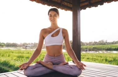Endonezya pirinç tarlalarının yakınında dinlenen neşeli kadın yogi portresi. Uyum meditasyonu için zaman harcayan mutlu beyaz kadın Tayland 'da sabah yoga antrenmanının keyfini çıkarıyor.
