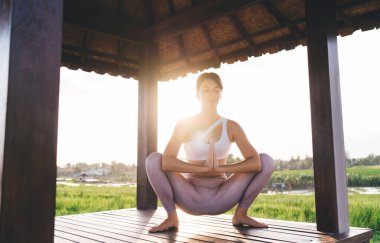 Namaste Asana 'da sakin bir kadın sabah vakti kaslarını esnetiyor güneş ışığı meditasyonunun keyfini çıkarıyor canlılık ve iç huzuru hissetmek için, beyaz kadın pilates yapıyor.