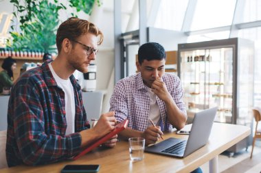 Ofiste dizüstü bilgisayardan bir şey izleyen çok ırklı iş adamları. İş birliği ve takım çalışması kavramı. Modern ve başarılı insanların fikirleri. Masada çalışan genç Asyalı ve beyaz adamlar.