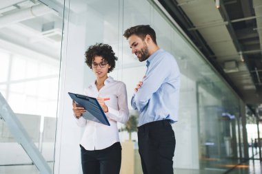 Çapraz kollu bir iş adamı, kadın meslektaşının panoya ne yazdığına bakıyor. İş birliği ve takım çalışması. Genç Kafkasyalı bin yıllık meslektaşlar görev başında. Modern başarılı insanlar