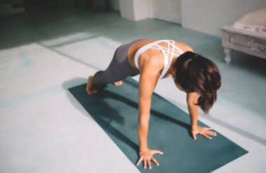 Plank pozisyonunda yoga yapan bir kadın. Uyum ve akıl sağlığı kavramı. Spor giyimli, spor ayakkabılı ve spor minderinde çıplak ayaklı güzel bir kız. Güneşli bir gün