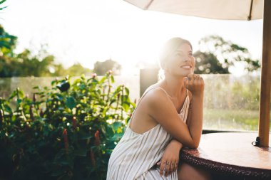 Kafkasyalı genç bir kadın otelin bahçesindeki masada oturup bir şeyler düşünüyor. Turizm, tatil ve hafta sonu. Dövmeleri olan güzel bir kız. Güneşli bir gün. Idyllic ve sakin yaşam tarzı