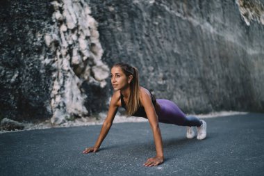 Genç beyaz kadın asfalt yoldan yukarı itiyor ısınıyor ve spor yapıyor, spor yapan kadın sağlıklı yaşam tarzına ve sağlığına ulaşmak için vücudunu aktif olarak inceltiyor ve formda tutuyor.