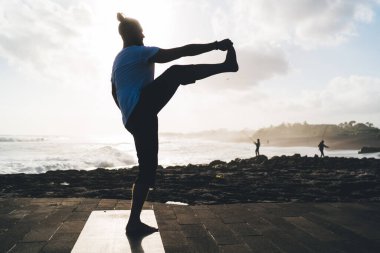 Spor giyim sektöründe esnek bir erkek, yaşam kalitesine ulaşmak için gün boyu sette yoga eğitimi alıyor, Kafkasyalı bir adam sabahları siyah mindere uzanıp sağlıklı yaşam tarzını koruyor.