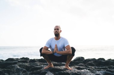Spor dalındaki yakışıklı beyaz yogi kıyı şeridi egzersizi sırasında meditasyon yapar zihin konsantrasyonu ve yatıştırma için, dengede duran genç erkek namaste zen çalışması sırasında dua eder.