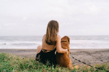 Kafkasyalı bir kadının, sevimli bir köpekle deniz kıyısında boş vaktini geçirmesi, kaygısız bir kadının, sevimli bir köpekle sahilde eğlenmesi ve açık havada arkadaşlığın tadını çıkarması.