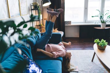 Evdeki kanepede uzanan Avrupalı kızın keyfini çıkarıyorum. Ev hayatı kavramı. Ev istirahatı ve boş zaman fikri. Gözleri kapalı, genç ve düşünceli bir kadın. Stüdyo dairenin içi.