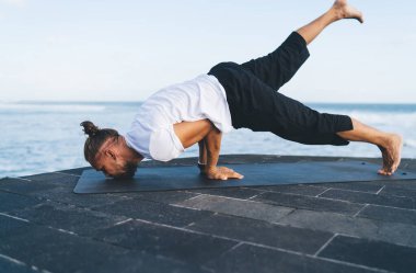 Sportif alandaki sakin adam yoga yaparken eğlenmekten zevk alıyor. Güçlü erkek, Asya 'da el ele tutuşup kaslarını esnetiyor ve sağlıklı yaşam tarzına ve dengeye ulaşıyor.