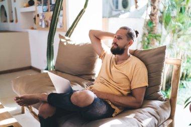 Modern dizüstü bilgisayar teknolojisine sahip tefekkür eden beyaz adam terasta uzaktan çalışırken program kodunu düşünüyor. Dijital netbook 'u olan düşünceli erkek programcı veri servisi üzerinde kafa yoruyor.