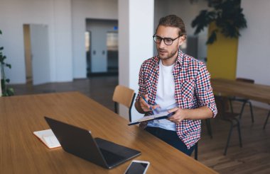 Ciddi bir erkek bilgi işlem uzmanı, dijital netbook bilgisayarında taranmış bilgileri analiz ediyor, modern dizüstü bilgisayarda veri kodlarını kontrol eden şaşkın bir programcı, birlikte çalışan alanda 4G kablosuz kullanıyor.