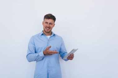 Modern dokunmatik cihazlı neşeli erkek çalışanın yarısı iş reklamları için fotokopi alanı olan tanıtım arkaplanının yanındaki kameraya gülümsüyor. Dijital tabletli başarılı girişimci.