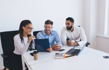 Kağıt notları tartışan çok kültürlü çalışanlardan oluşan bir grup, ofis içi toplantıdaki brifing istatistiklerini analiz ederken, genç meslektaşlar ticaret değişimi ve CEO mesleği hakkında konuşuyorlar.