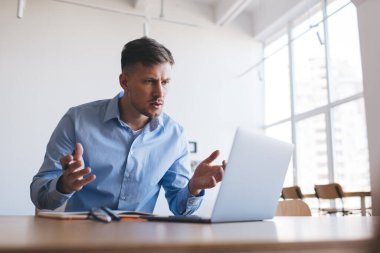 Eğitimli beyaz erkek öğrenci netbook üzerinde çalışırken kaşlarını allak bullak etmiş, kafası karışmış hipster çocuk ve birlikte çalışma alanında dizüstü bilgisayarda 4G kablosuz internet kullanarak öğreniyor.