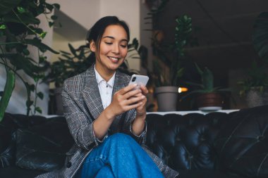 Cep telefonuyla 4G 'ye bağlanan mutlu Asyalı kadın blogcu cep telefonundan mesaj atıyor, neşeli hippi kız akıllı telefondan mobil uygulamayla online rezervasyon yapıyor - web iletişiminin tadını çıkarıyor