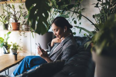 Milenyum kadın blogger ağı mobil uygulama tarayıcı web sitesi üzerinden kayıt podcast ile, bluetooth kulaklık takan Asyalı kadın müzik listesi dinliyor ve cep telefonundan sesli mesaj alıyor