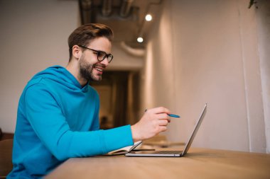 Sosyal medyada video içeriğini arayan neşeli Kafkasyalı öğrenci serbest dizüstü bilgisayar kullanıyor, gözlüklü erkek bilişim uzmanı bankacılık için netbook üzerinden 4G kablosuz internete bağlanıyor