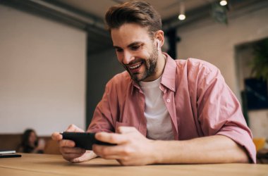 Elektronik kulaklıklı mutlu beyaz adam, Nintendo konsol teknolojisi ile online oyun oynadığı için boş zamanların tadını çıkarıyor, akıllı telefondan 4G 'ye bağlanan neşeli erkek kullanıcı,