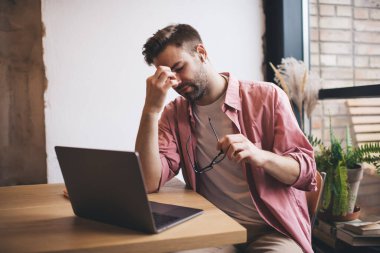 Elektronik kulaklıklar takan Kafkasyalı bilişim uzmanı, son teslim tarihi sırasında baş ağrısı hissediyor. Kafenin içinde çalışıyor, yorgun erkek programcı dizüstü bilgisayarlı, fazla mesai sırasında ses kitabı dinliyor.