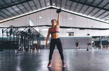 Spor giyim sektöründe güçlü bir kadın halter antrenmanı yapıyor. Spor salonunda halter antrenmanı yapıyor. Spor salonunda halterci kadın halter egzersizi yapıyor.