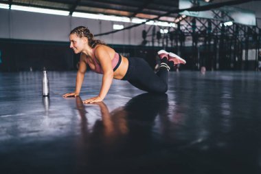 Mutlu beyaz bayan sporcu şınav çekiyor kaslarını ısıtmak için antrenman yapıyor, gülümsüyor formda kız spor salonunda egzersiz yapıyor ve fiziksel güç uyguluyor.