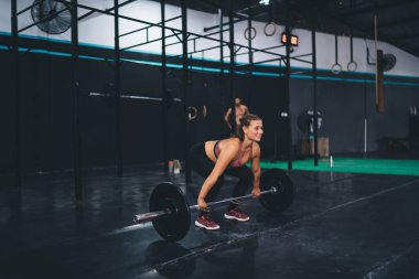 Spor giyimli beyaz bir sporcu ağırlık kaldırırken ağırlık kaldırıyor. Stüdyoda ağırlık kaldırma egzersizi yapıyor. Vücut geliştirici, vücut şeklini sağlıklı yaşam tarzına ve çapraz forma sokuyor.