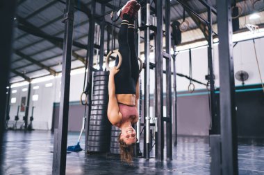 Jimnastik yüzükleriyle kameraya gülümseyen neşeli dengeli bayan sporcunun portresi. Spor ve sağlıklı yaşam tarzından memnun, spor salonunda vücut geliştirme eğitiminden mutlu.