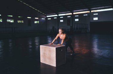 Spor kıyafetleri içinde beyaz bir sporcu atlama kutusuna yakın bir yerde spor salonu eğitimi için hafta sonu boş vaktini harcıyor genç bir kadın zayıflıyor ve vücut şeklini tonusta koruyor. Dayanıklılık.