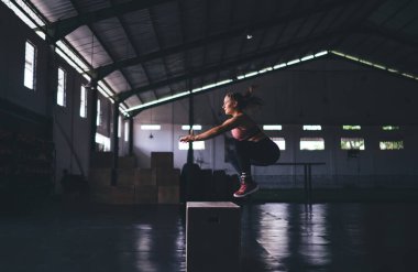 Aktif olarak giyinen beyaz kadın spor salonunda ısınma egzersizleri yapıyor. Spor stüdyosunda zayıflama antrenmanı sırasında kaslı vücut şekli olan kararlı bir kadın kutuya atlıyor.