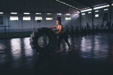 Ağır lastikli kadın vücut geliştirici spor salonu içinde zayıflamak için kardiyo eğitimi almış. Tekerlek teçhizatlı beyaz kadın sağlıklı yaşam tarzını ve canlılığını koruyor.