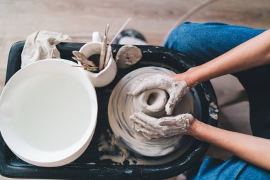 Kadın heykeltraşın çömlek çarkında kil çömlek yaptığı kısmi görüntü. Küçük işletme ve girişimcilik kavramı. Ev hobisi, eğlence ve eğlence. Sanat stüdyosu. 50 yaşındaki bir kadının en iyi görüntüsü.