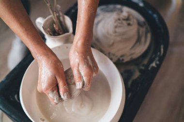 Sanat atölyesindeki seramik çömlek kalıbını çıkardıktan sonra kadın ustanın suda ahşap aletleri yıkadığı kısmi görüntü. Küçük işletme ve girişimcilik kavramı. Ev hobisi, eğlence ve boş zaman fikri