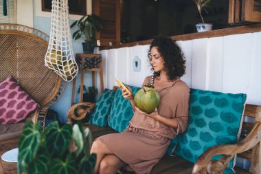 Sosyal medyada sohbet etmek ve mesajlaşmak için cep telefonu aygıtı kullanan, tropik içeceği olan beyaz bir kadın, modern akıllı telefonlu, internet sitesi için 4G kablosuz ağa bağlanan bin yıllık bir kadın.