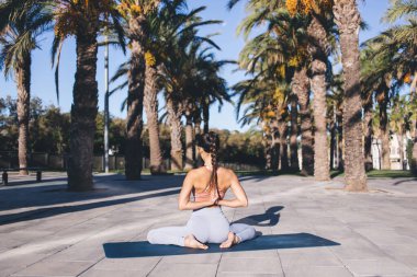 Eşofmanlı genç Asyalı bir kadının namaste 'de el ele tutuşup bütünsel iyileşme sırasında iç huzur ve farkındalık arayışı içinde olması.