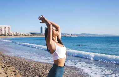 Sakin Asyalı kadın namaste 'de dua etmeye devam ediyor. Deniz kıyısında meditasyon yaparken güneş enerjisi alıyor. Beyazlar içindeki genç kadın yoga mantraları sırasında zen ve farkındalık hissediyor.