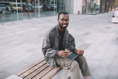 Uzaktan kumandayla çalışan mutlu dijital göçebe portresi, modern dizüstü bilgisayar teknolojisi olan neşeli erkek blogcu serbest meslek yaparken poz veriyor.