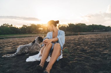 Mutlu Kafkasyalı bir kadın, sevimli köpek yavrusuyla eğleniyor. Deniz kıyısındaki kumsalda boş vaktini geçiriyor. Kaygısız bir kadın, sahil şeridinde sevimli bir köpekle eğleniyor.