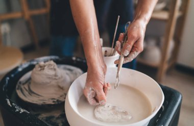 Sanat atölyesinde seramik çömlek kalıbını çıkardıktan sonra kadın ustanın suda ahşap aletleri yıkadığı kısmi görüntü. Küçük işletme ve girişimcilik kavramı. Ev hobisi, eğlence ve eğlence