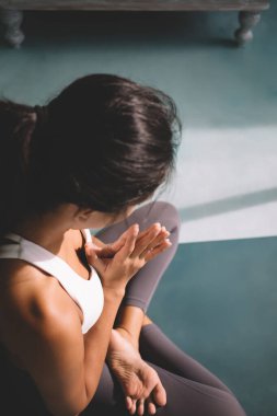 Ateşin kütüğünde yoga yapan bir kadının kısmi görüntüsü geniş bir evde poz veriyor. Uyum ve akıl sağlığı kavramı. Spor kıyafetleri giyen esmer bir kız ve spor minderinde yalınayak.