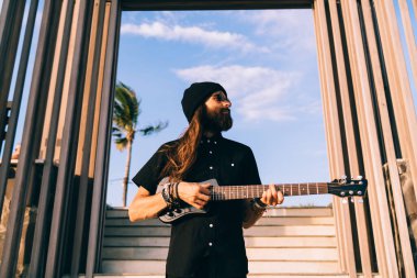 Ukulele enstrümanlı amatör hippi hafta sonu açık havada şarkı çalmaktan zevk alıyor Hawaii gitarlı beyaz adam hobisiyle eğlenmek için müzik meditasyonu sırasında şarkı söylüyor.